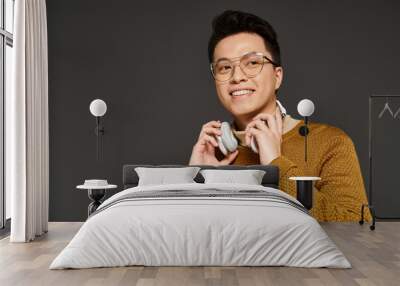 A fashionable young man in elegant attire with headphones and wearing glasses. Wall mural