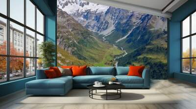 A full shot of a picturesque mountain range viewed from a high angle. The photograph captures the rugged peaks and rolling valleys, with snow-capped summits and lush green valleys extending far into Wall mural