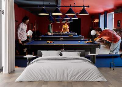 A group of friends playing billiards in a dimly lit pool hall. Wall mural