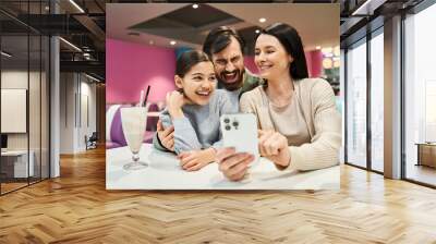 A joyful family gathers at a restaurant, happily taking a selfie together to preserve their weekend memories. Wall mural