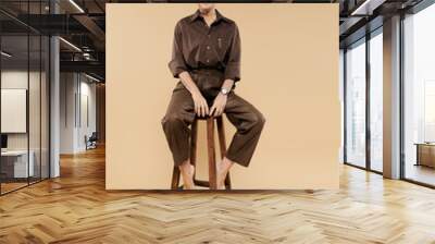 A mature woman with short hair in elegant attire sitting on tall chair. Wall mural