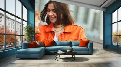 A stylish man and woman stand side by side, both wearing bold orange jackets Wall mural