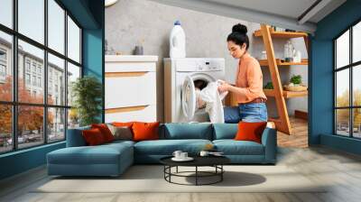 A stylish woman in casual attire sitting beside a washing machine, taking a moment of calm amidst the chore of doing laundry. Wall mural