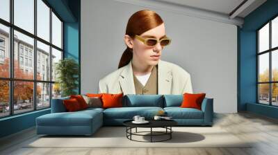 A teenage boy with striking red hair confidently poses in a chic smart casual ensemble in a sleek studio. Wall mural