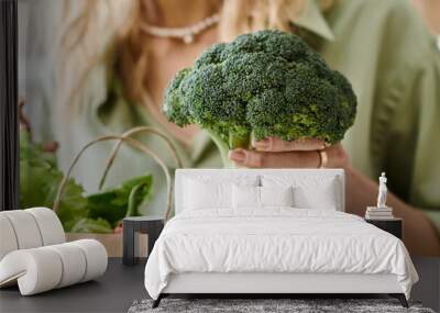 A woman in an apartment holding a bag full of fresh vegetables. Wall mural