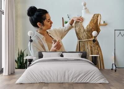 A woman in casual attire is crafting a dress on a mannequin. Wall mural