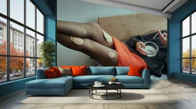 A woman in stylish grungy attire lounges on a bed, relaxing in a comfortable and casual setting. Wall mural