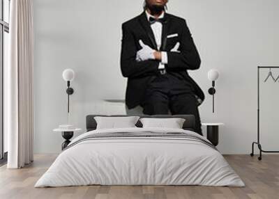 A young man dressed in a sharp suit and vest exudes elegance as he poses confidently on a grey background. Wall mural