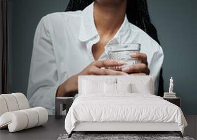 A young woman in a crisp white shirt sits with a drink and a thoughtful expression. Wall mural