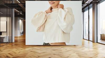 A young woman radiates confidence, posing gracefully in her fashionable autumn attire within a warm studio environment. Wall mural