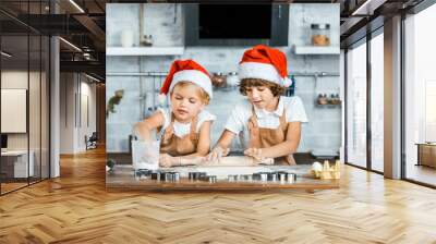 adorable chldren in santa hats and aprons preparing christmas cookies together Wall mural