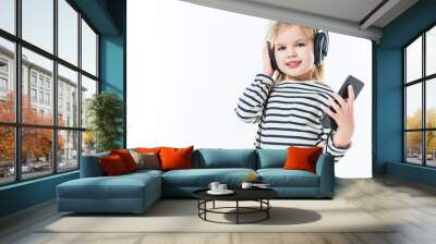 adorable little child listening music with headphones and smartphone isolated on white Wall mural