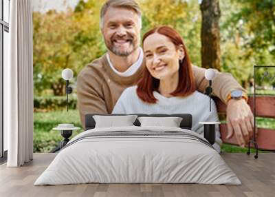 Adult couple in casual attire enjoying a peaceful moment on a park bench. Wall mural