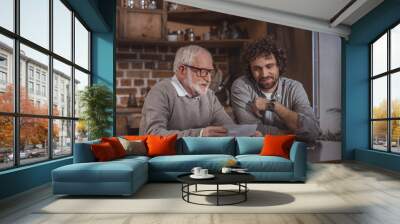 adult son and senior father looking at old photos at home Wall mural