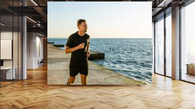 adult sportsman jogging on seashore in morning Wall mural