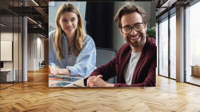 African american businesswoman smiling at colleagues near documents in office, banner Wall mural