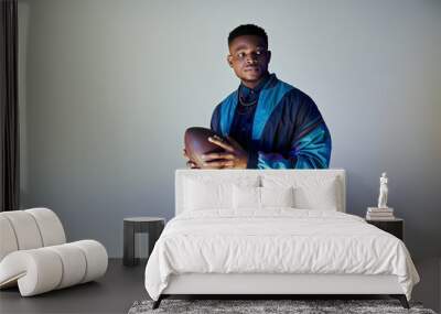 African American man in fashionable attire holding a football. Wall mural