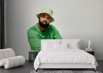 African American man in green shirt and hat sitting outdoors. Wall mural