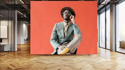 african american man in vintage eyeglasses talking on smartphone, isolated on red Wall mural