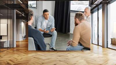 African american man with alcohol addiction sharing problem during group therapy session in rehab center. Wall mural