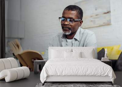 african american mature man in glasses reading book Wall mural