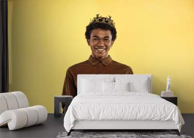 african american teenage boy in crown smiling while holding presents isolated on yellow Wall mural