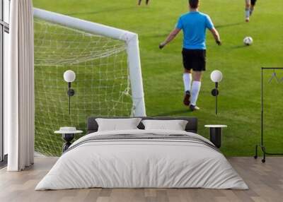 An aerial shot of a soccer goal during a penalty kick, with shallow focus highlighting the player about to shoot, while the goalkeeper and background become softly blurred Wall mural