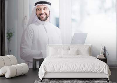 Arabian businessman holding laptop in modern office Wall mural