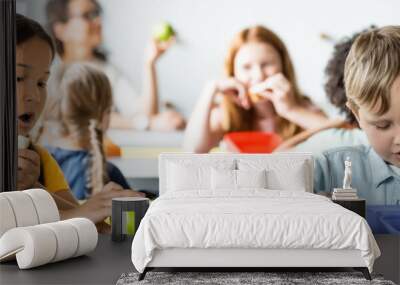 asian schoolgirl eating sandwich near classmates during lunch break, banner Wall mural