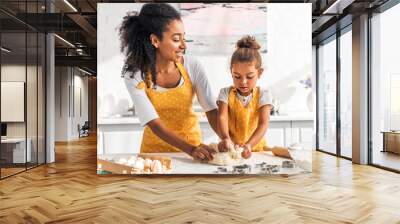 attractive african american mother and adorable daughter kneading dough in kitchen Wall mural