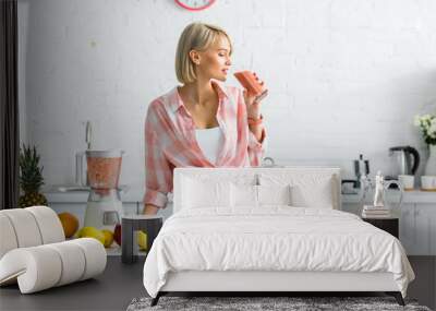 attractive blonde woman drinking tasty smoothie near ingredients in kitchen Wall mural