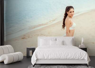 attractive brunette girl posing in white bikini on sandy beach at sea Wall mural