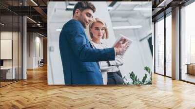 attractive businesswoman and smiling businessman using digital tablet together Wall mural