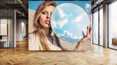 attractive elegant model holding round mirror with reflection of cloudy sky Wall mural