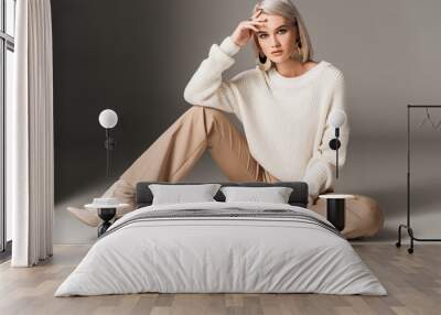 attractive fashionable woman posing in white trendy sweater, beige pants and autumn heels, on grey Wall mural