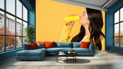 attractive girl drinking soda from can, isolated on yellow Wall mural