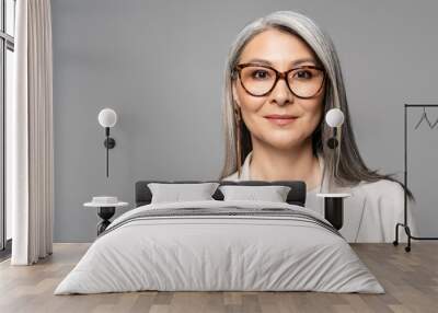 attractive smiling asian businesswoman in eyeglasses isolated on grey Wall mural