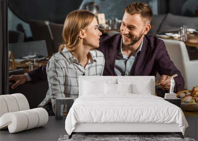 Attractive smiling couple amorously looking at each other while having dinner in restaurant Wall mural