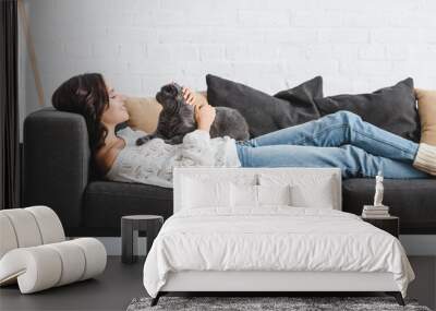 attractive woman lying on sofa with scottish fold cat in cozy living room Wall mural