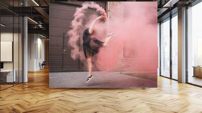 attractive young woman dancing in pink smoke on street Wall mural