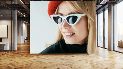 Attractive young woman in red beret and sunglasses isolated on grey Wall mural