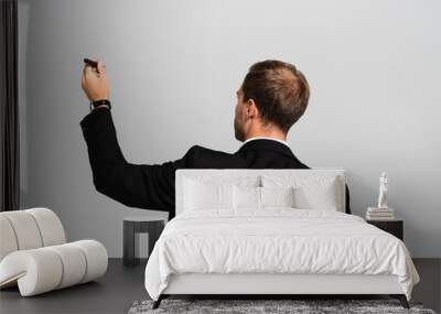 back view of businessman in suit holding marker isolated on grey Wall mural