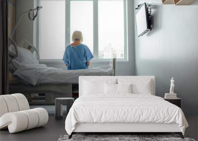 back view of lonely senior woman sitting on bed in hospital ward with copy space Wall mural