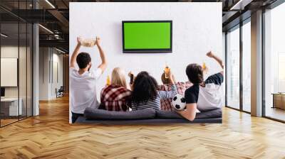 back view of multicultural football fans watching championship on tv and showing winner gesture Wall mural