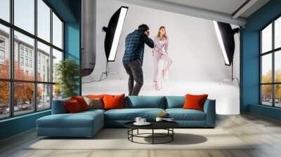 back view of photographer shooting beautiful young female model in photo studio Wall mural