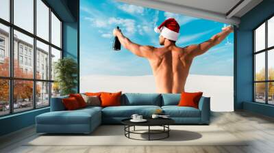 back view of sexy man in santa hat holding glass and bottle on beach in Maldives Wall mural