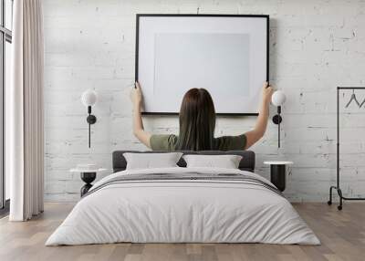 back view of woman holding blank black frame in hands Wall mural