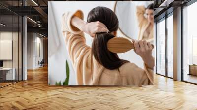 back view of young brunette woman brushing hair in bathroom. Wall mural