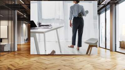 back view of young businesswoman holding yoga mat in office Wall mural