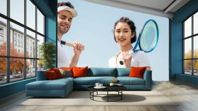 banner, happy couple in sportswear standing with tennis rackets on court, looking at camera, sport Wall mural